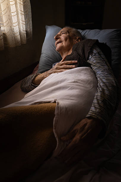 istock Elderly man lying in bed with a serene expression, illuminated by natural light from a nearby window 2219761093