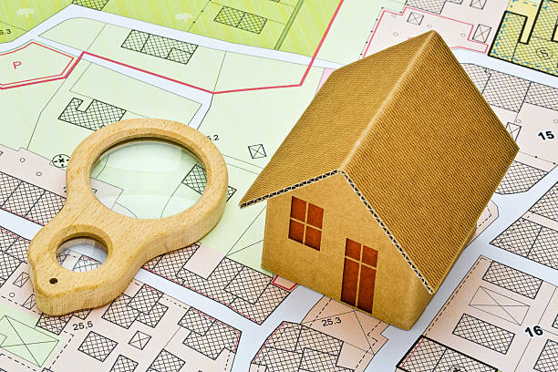 istock Imaginary cadastral map with buildings, land parcel and vacant plot - property registry and real estate concept with a wooden magnifying glass - note: the map background is totally invented and does not represent any real place 2219762766