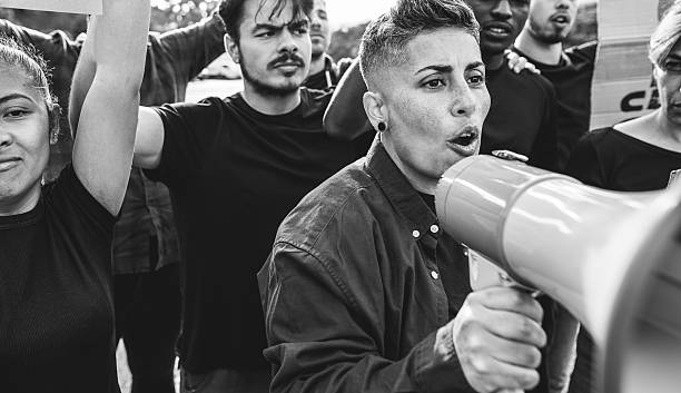 istock Multiracial immigrants protesting outdoor against government laws - Riot, demonstration and activits concept - Main focus on center woman face - Black and white editing 2219768555