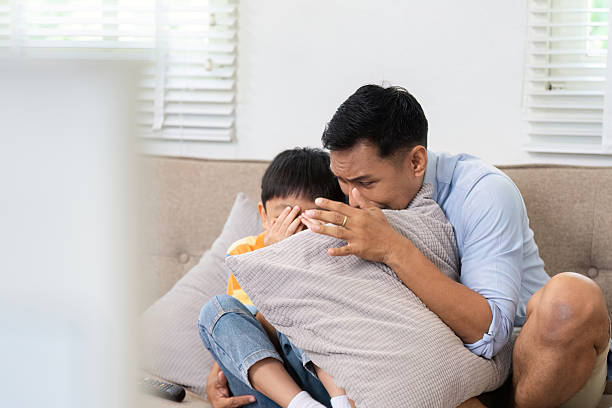istock Scared Child Comforted by Father. A father and son share a tense moment while watching a scary movie. 2219768901