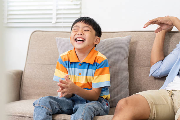 istock Family Bonding and Joy. A boy laughing with his father while sitting on a couch. 2219768927