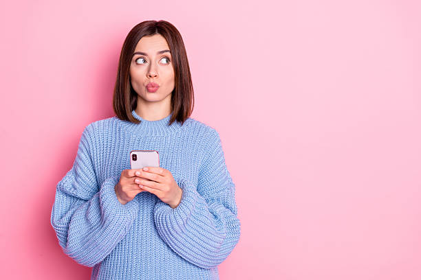 istock Portrait of attractive minded funky girl influencer using gadget thinking post copy space pout lips isolated over pink pastel color background 2219769042