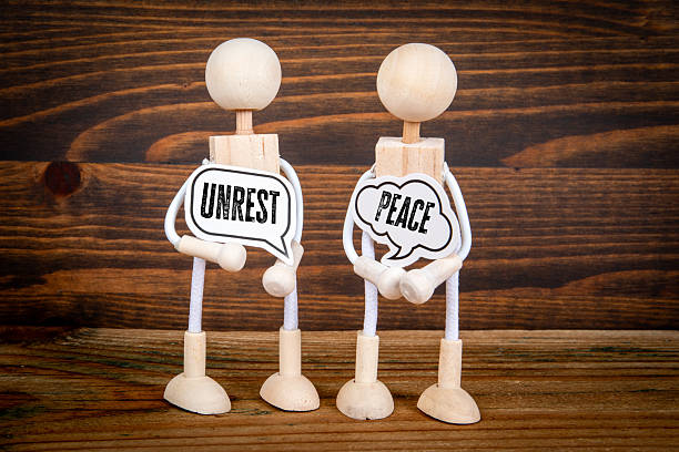 Contrast Between Peace and Unrest Represented by Wooden Figures Holding Speech Bubble Signs.
