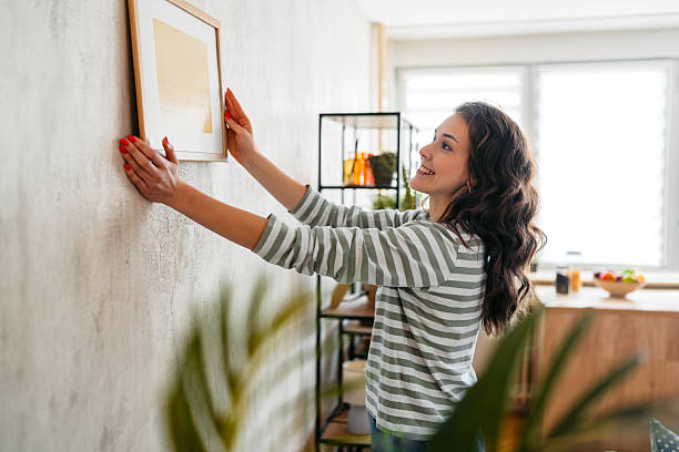 istock Young Woman Hanging A Picture Up On The Wall 2219773208