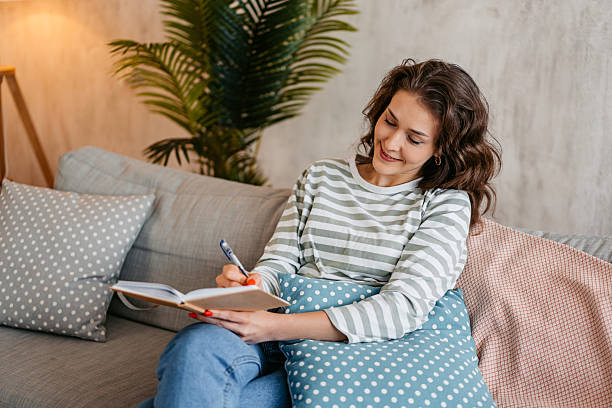 istock Young Woman Writing In A Diary At Home 2219773593