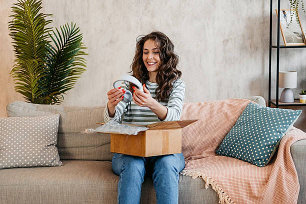 Young Woman Unboxing A Package With New Headphones She Ordered Online