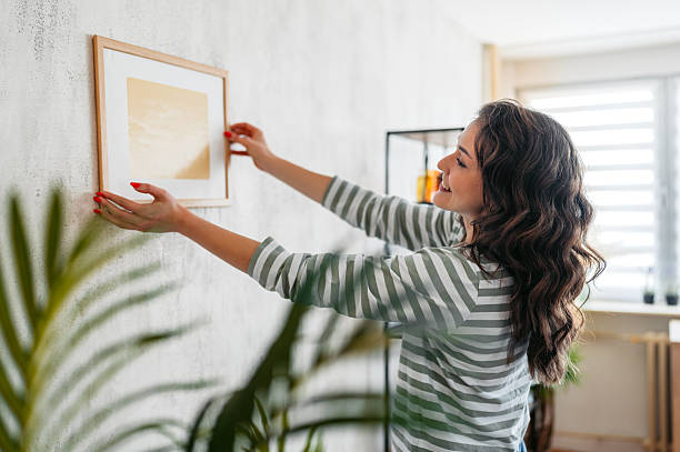 istock Young Woman Hanging A Picture Up On The Wall 2219773784