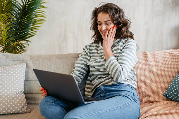 istock Young Woman Watching Something Funny On The Laptop At Home 2219774849