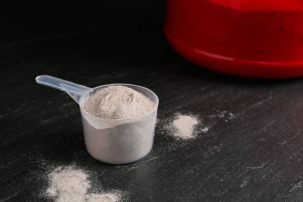 istock Protein powder in scoop on grey textured table, space for text 2219776234