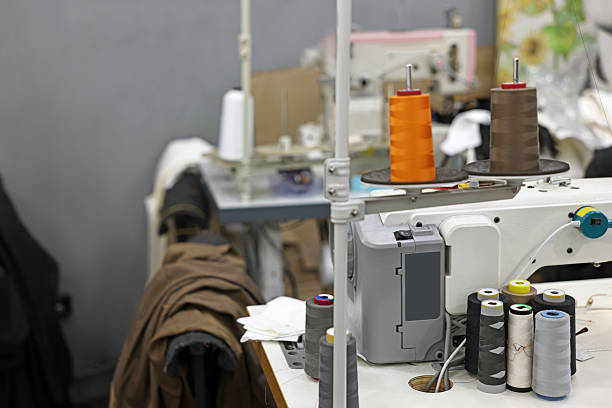Sewing machines with spools of thread in professional workshop, closeup