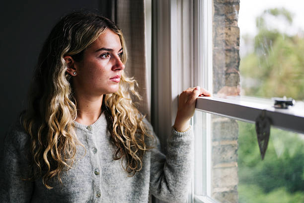 istock Young woman looking out the window with contemplation 2219776865