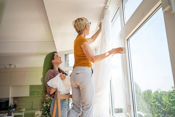 istock Women hanging curtains on window in new home 2219783178