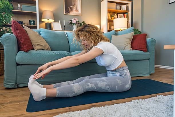 istock Young female student exercising at home to relieve back pain from long study hours, using online workout programs while sitting near laptop, focusing on health and posture improvement 2219783444