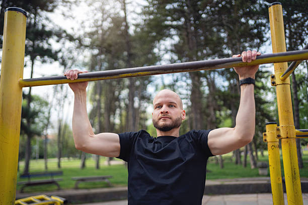 istock Man performing outdoor bodyweight exercise on bar in a park setting 2219783715