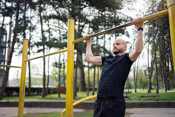 istock Man performing pull-ups on outdoor equipment in a park 2219783753