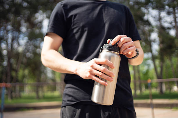 istock Man opening water bottle outdoors during fitness workout in a park setting 2219783816