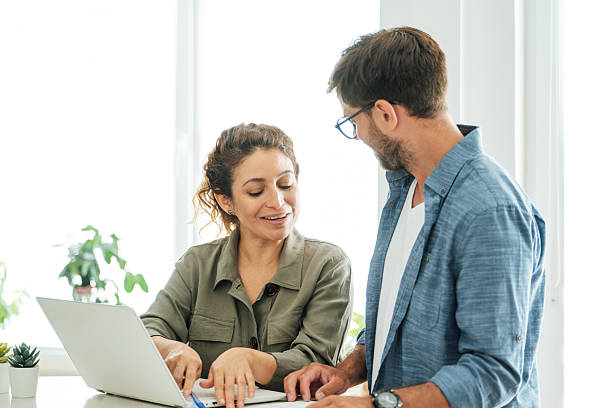 istock Two colleagues engage in a collaborative discussion at an office desk with a laptop and documents in a bright modern workspace 2219784081