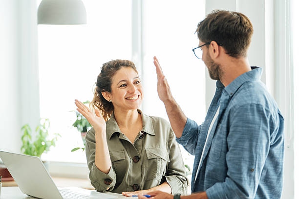 istock Two colleagues engage in a collaborative discussion at an office desk with a laptop and documents in a bright modern workspace 2219784087