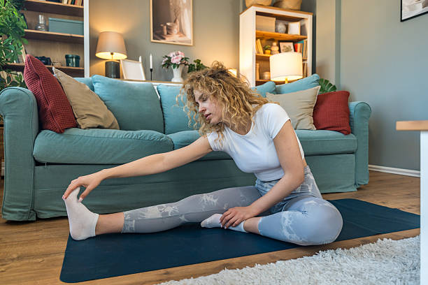 istock Young female student exercising at home to relieve back pain from long study hours, using online workout programs while sitting near laptop, focusing on health and posture improvement 2219784097