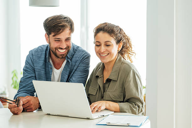 istock Two colleagues engage in a collaborative discussion at an office desk with a laptop and documents in a bright modern workspace 2219784102