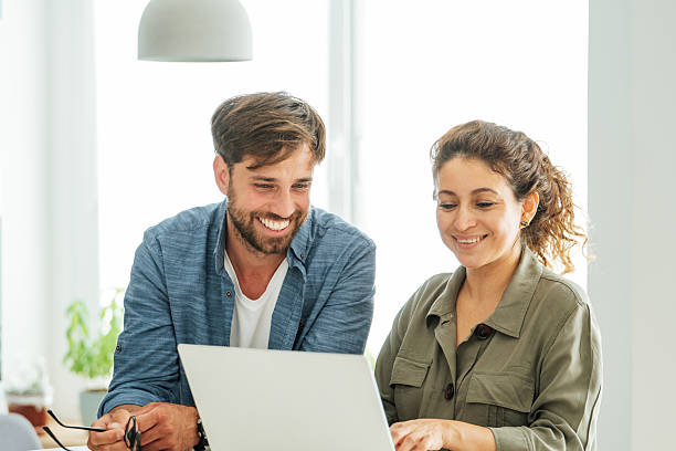 istock Two colleagues engage in a collaborative discussion at an office desk with a laptop and documents in a bright modern workspace 2219784108