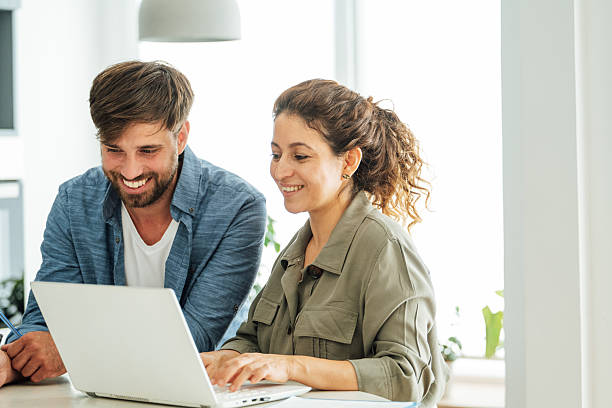istock Two colleagues engage in a collaborative discussion at an office desk with a laptop and documents in a bright modern workspace 2219784117