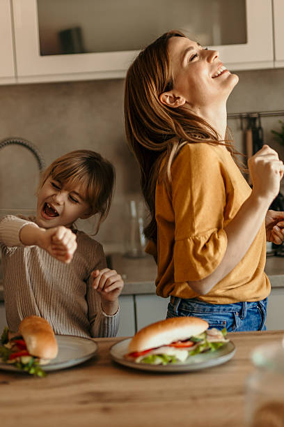 istock Mother and daughter dancing in the kitchen while having sandwiches for lunch 2219785949