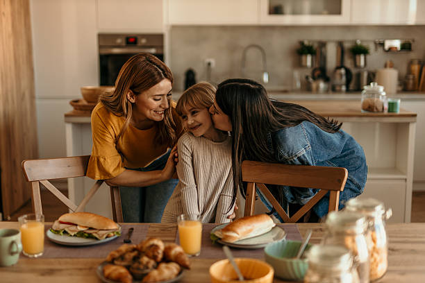 istock Two mothers showing affection to their daughter during breakfast in the kitchen 2219787558