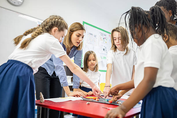 istock Group of School Children and Teacher Collaborating on Classroom Project 2219788481