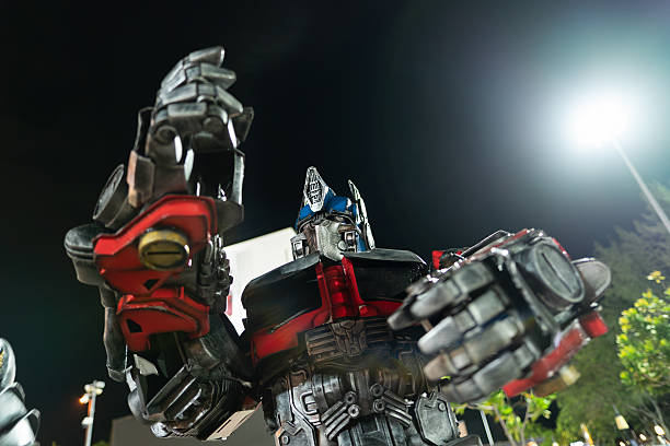 Langkawi, Malaysia - September 11, 2024: Optimus Prime costumed performer at Pantai Cenang, Langkawi, moving slightly to music in the night. Performer in a heavy grey, red and blue costume.