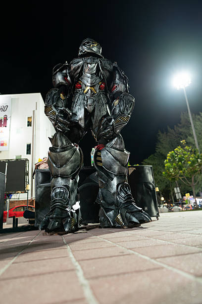 Langkawi, Malaysia - September 11, 2024: Megatron costumed performer at Pantai Cenang, Langkawi, moving slightly to music in the night. Performer in a heavy gray and red costume.