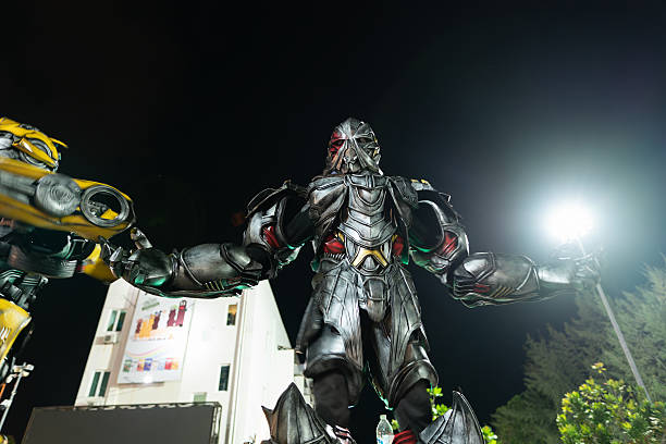 Langkawi, Malaysia - September 11, 2024: Megatron costumed performer at Pantai Cenang, Langkawi, moving slightly to music in the night. Performer in a heavy gray and red costume.