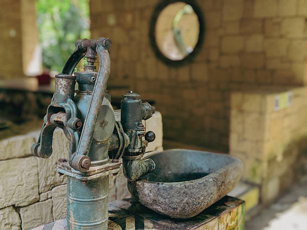 An old-fashioned hand water pump is a manually operated device used to draw water from a well or underground source