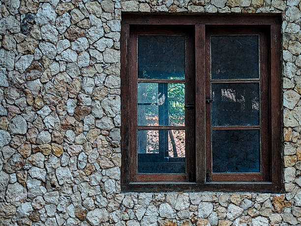 Close-up view of a weathered stone building in the abandoned village of Malo Grablje, located on the island of Hvar, Croatia. The crumbling facade and empty window frames tell stories of a once-vibrant settlement now overtaken by time. This striking image captures the textures and heritage of Mediterranean architecture in a deserted rural environment.