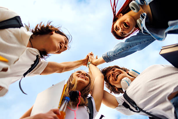 istock Happy students joining hands celebrating success outdoors 2219794843