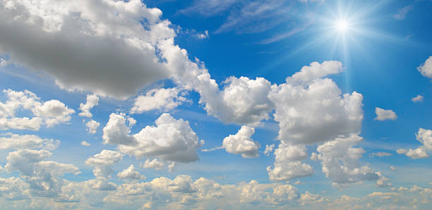 Bright sun and white clouds in clear blue sky on summer day.