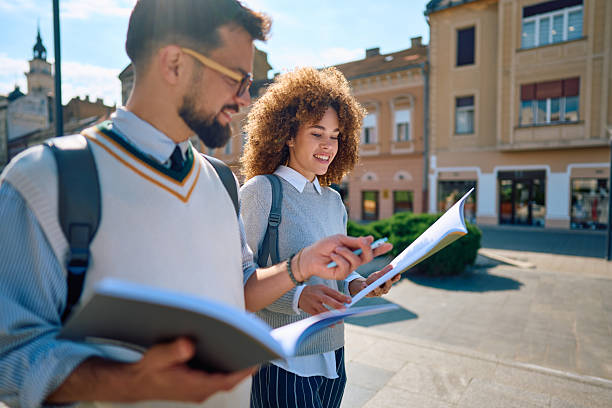 istock Students walking and reading a book in a city street 2219801121