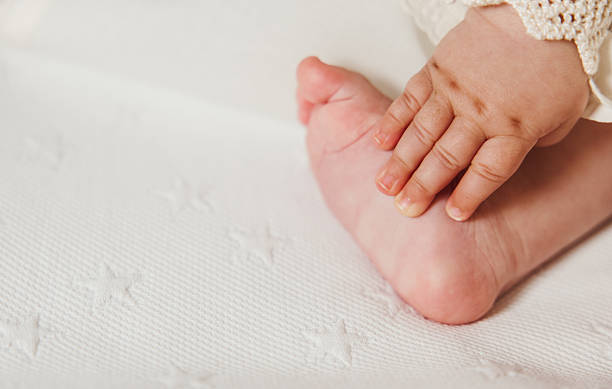 istock Baby hand holding foot on white blanket with copy space 2219801247