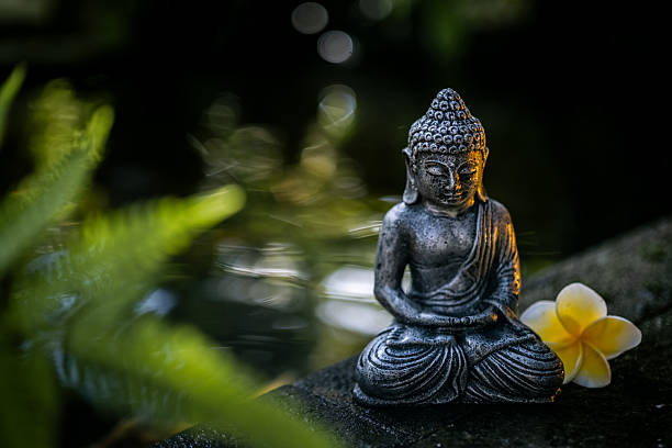 A serene Buddha statue sits peacefully by a koi pond, symbolizing mindfulness, tranquility, and spiritual meditation in nature. Bali, Indonesia.