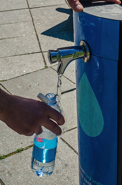 istock Filling reusable bottle with fresh drinking water from a public tap 2219810420