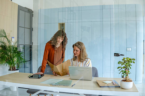 istock Businesswomen collaborating in a modern office setting while reviewing documents 2219812139