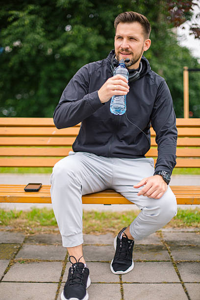 istock Sportsman drinking water after training outdoors in park 2219813395