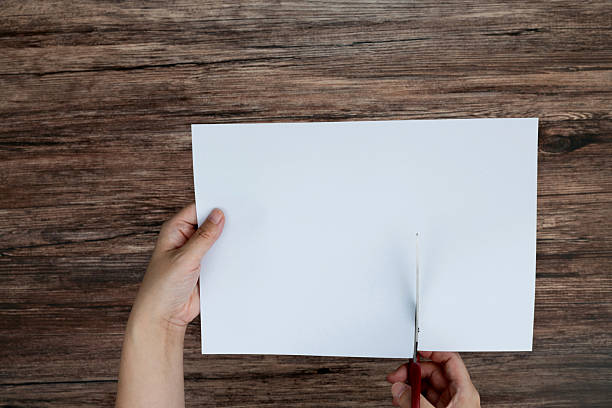istock Scissors cutting a piece of blank paper 2219813906