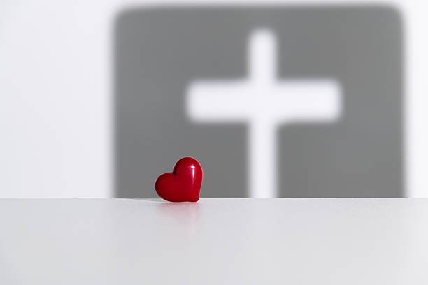 Religious cross shadow and red heart on white background
