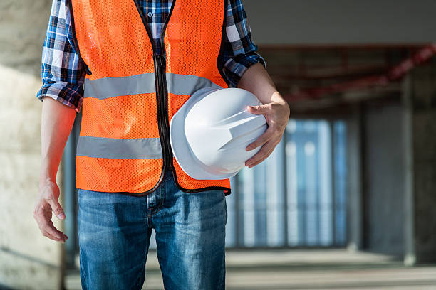 istock Close up of male construction worker holding white hardhat 2219814512