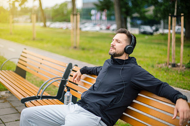 istock Runner relaxing on bench listening to music after workout 2219815164