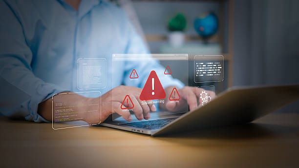 istock Cybersecurity, virus protection, Hand on laptop with holographic System warning and red alert icons. Symbolizes cyber threats, data security breaches, and IT system errors. digital risk management now 2219815631