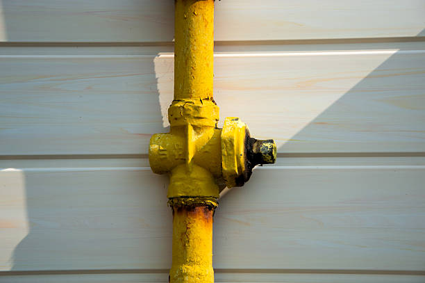istock A yellow pipe fitting is affixed to a white surface, illuminated by afternoon sunlight, showing wear and industrial design 2219816686