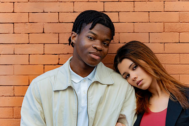 istock Young couple leaning against brick wall embracing each other 2219818078