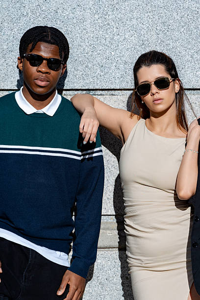 istock Fashionable models posing against gray wall, embracing urban style 2219818093